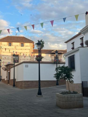 a courtyard with two buildings and a street light with flags at Apartamento Turístico Julia Gemella Acci in Guadix