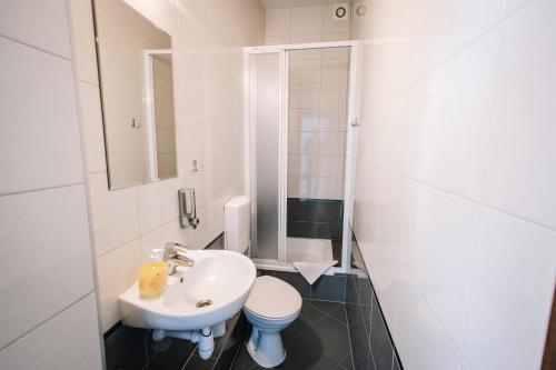 a white bathroom with a sink and a toilet at DW Turysta in Licheń Stary