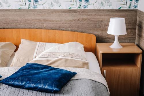 a bed with a blue pillow and a lamp on a night stand at DW Turysta in Licheń Stary