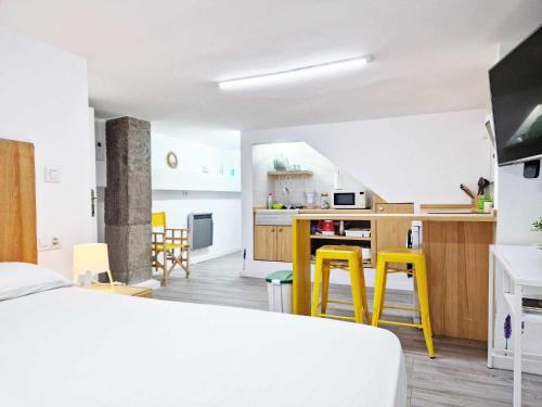 um quarto com uma cama e uma cozinha com bancos amarelos em Studio Simon 1 Murcia em Múrcia