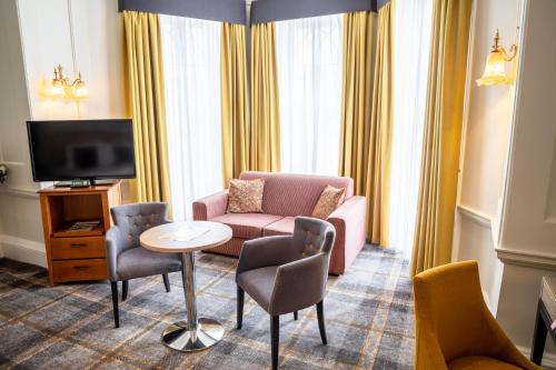 a living room with a couch and chairs and a tv at Arnos Manor Hotel in Bristol