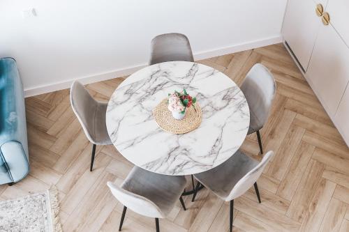 a marble table with chairs and a bowl of flowers on it at Genio apartamentai Kunigiskiuose in Palanga