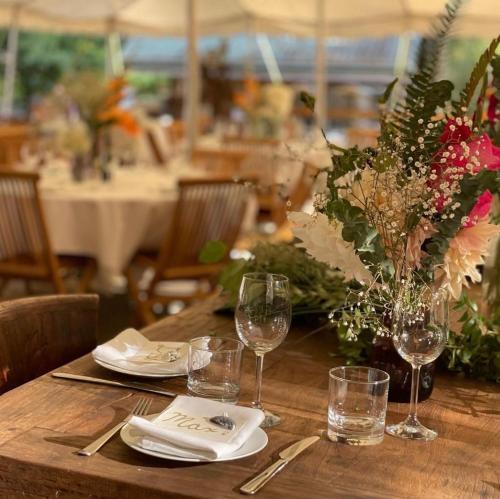 einem Holztisch mit Weingläsern und einer Vase aus Blumen in der Unterkunft Ruby Lake Resort in Madeira Park