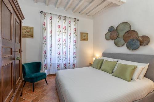 a bedroom with a white bed and a green chair at Tina’s House in Cortona