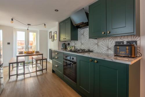 a kitchen with green cabinets and a wooden floor at Stylish Southampton City Centre House in Southampton