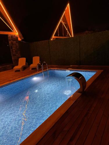 a swimming pool at night with two chairs around it at ROSE SAPANCA STONE HOUSE in Sakarya