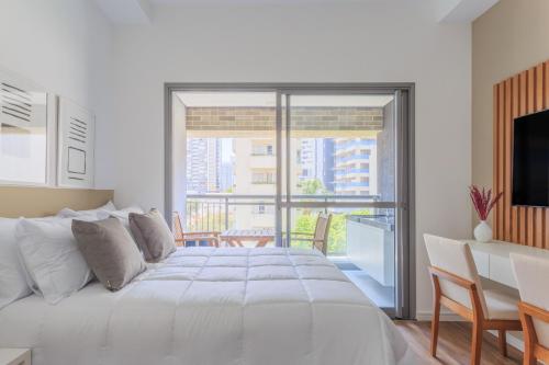 um quarto branco com uma cama grande e uma varanda em Tabas - Edifício Z. Pinheiros em São Paulo