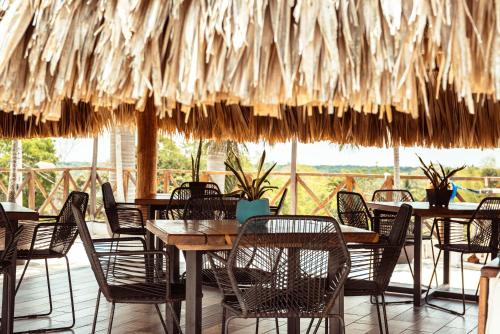 Xul-HaにあるHotel y Beach Club Casa Mia Xulha -Bacalarのテーブル、椅子、藁の傘が備わるレストラン