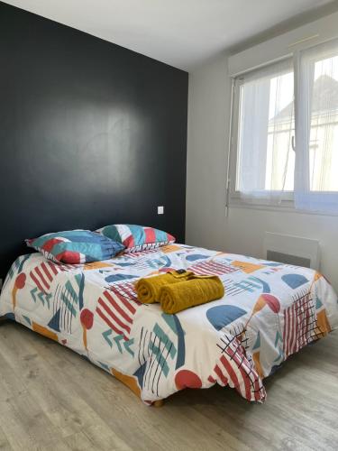 ein Schlafzimmer mit einem Bett mit einer bunten Bettdecke in der Unterkunft Appart43m² Proche Gare et Centre in Cholet