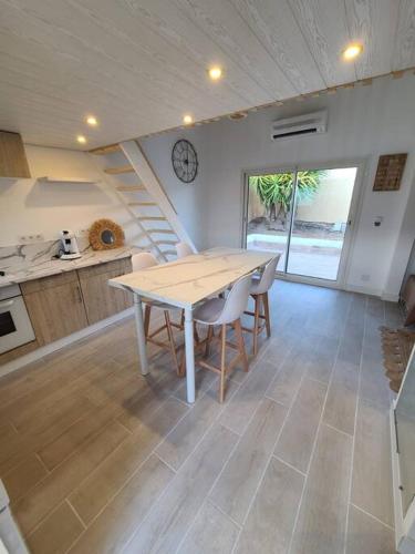 une cuisine avec une table, des chaises et une horloge dans l'établissement Maison pleine de charme avec grand jacuzzi privé, au Cap d'Agde