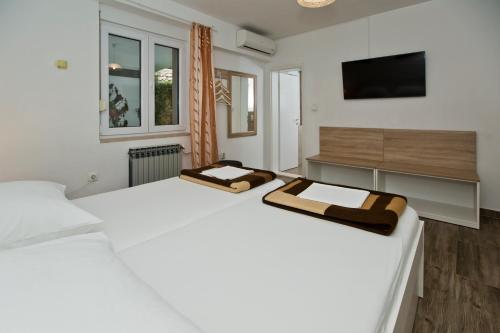 Habitación blanca con 2 camas y TV. en Guesthouse Aurora en Hvar