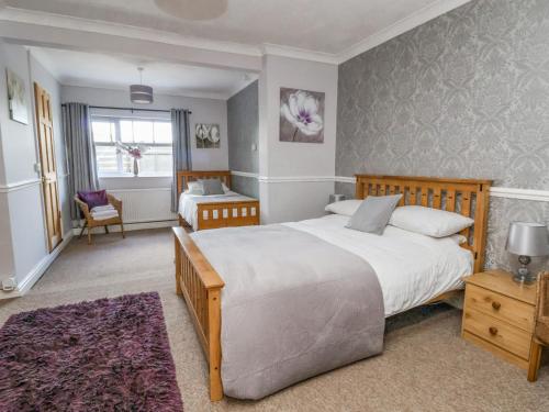 a bedroom with a large bed and a chair at Beach Cottage in Rhyl