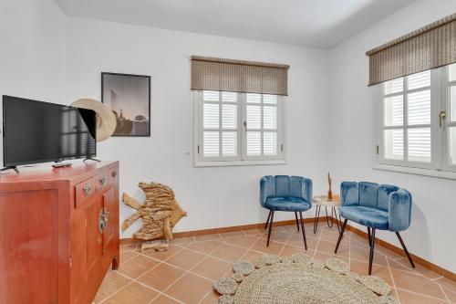 een woonkamer met twee blauwe stoelen en een televisie bij Villa Aventura in Kralendijk