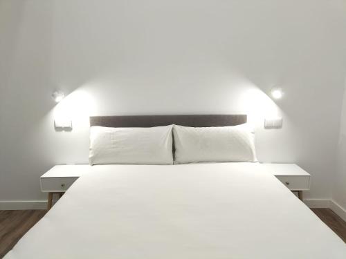 1 dormitorio con 1 cama blanca grande y 2 lámparas en Apartamentos Vacceas by gaiarooms, en Salamanca