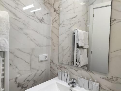 Baño blanco con lavabo y espejo en Apartamentos Vacceas by gaiarooms, en Salamanca