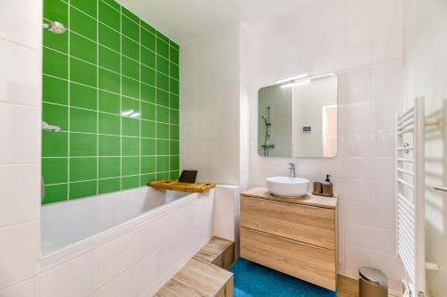 y baño con azulejos verdes, bañera y lavamanos. en L'élégance- Centre Historique- Confort- Netflix- Marché Frais et Local, en Grenoble