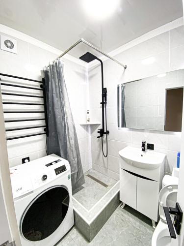 bagno bianco con doccia e lavandino di Квартира в центре города a Nukus