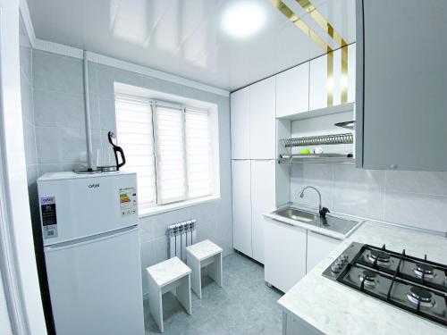 uma cozinha branca com um frigorífico e um lavatório em Квартира в центре города em Nukus