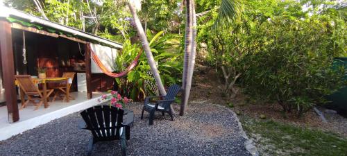 two chairs and a table in front of a house at bungalow tout confort avec piscine partagee à 5 mn de la mer in Saint-François