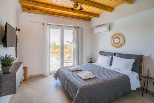 1 dormitorio con cama y ventana grande en Elianthos Luxury Villas, en Tsoukaladhes