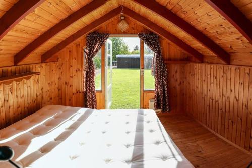 Cama grande en habitación de madera con ventana en Bright summer house close to the beach and water en Holbæk