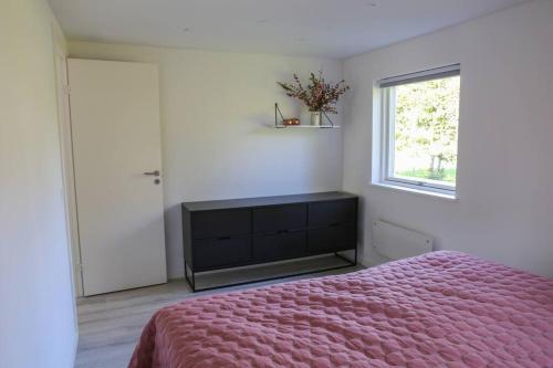 a bedroom with a pink bed and a window at Bright summer house close to the beach and water in Holbæk