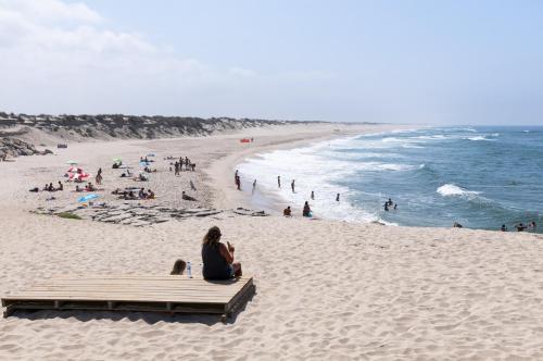 una mujer sentada en un banco en una playa en Brisa do Mar, en Vagos