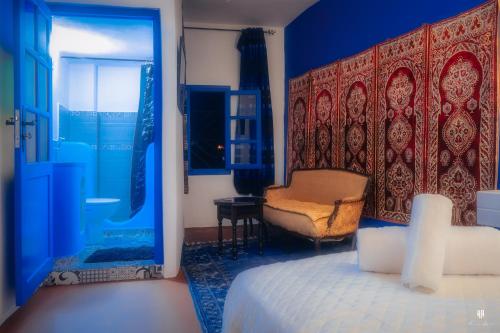 a bedroom with a bed and a chair and a window at CASA TROUSSI in Chefchaouen