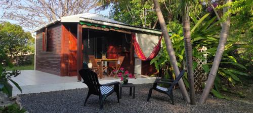 a small cabin with two chairs and a table in front of it at bungalow tout confort avec piscine partagee à 5 mn de la mer in Saint-François