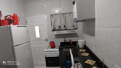 a small kitchen with a stove and a refrigerator at Casa Completa com Garagem a 400mts da basilica in Aparecida