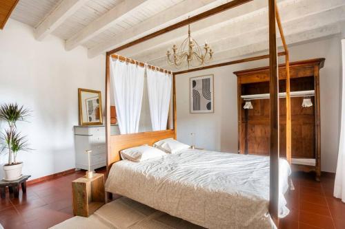 1 dormitorio con cama con dosel y lámpara de araña en Maison typique et de caractère au cœur d'un des plus beaux villages de France en La Roque-sur-Cèze