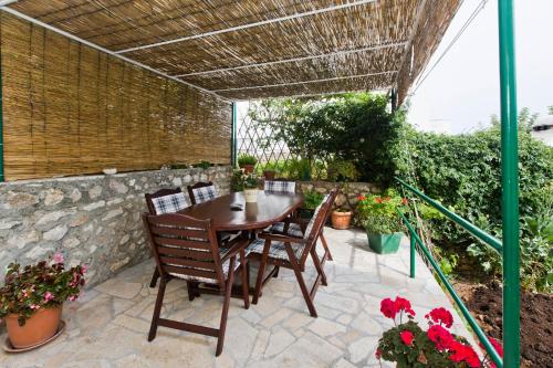 a patio with a wooden table and chairs and flowers at Guesthouse Aurora in Hvar