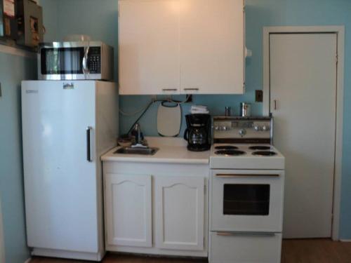 a kitchen with white cabinets and a white refrigerator at 2 bdrm country cottage - The Bait - Rosewood cottages in Southampton