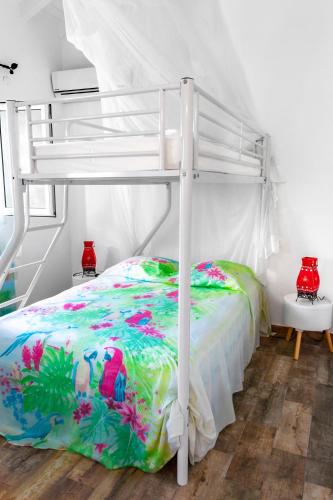 a bedroom with a white bunk bed with a colorful bedspread at Les gites du plateau de gissac in Sainte-Anne