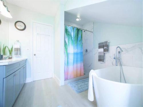 Southwinds Vacation Home في East End: حمام مع حوض استحمام وستارة دش ملونة