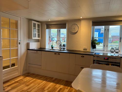 una cocina con armarios blancos y un reloj en la pared en Cory & Torfinn House, en Sørvágur