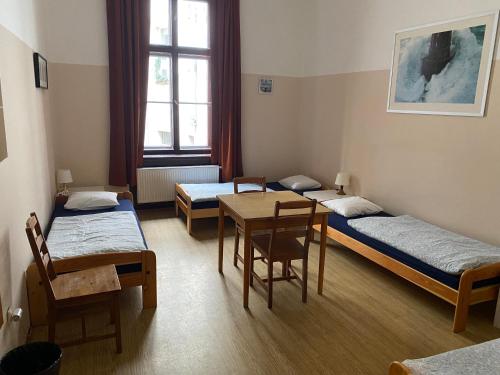 プラハにあるホステル エマのベッド3台、テーブル、椅子が備わる客室です。