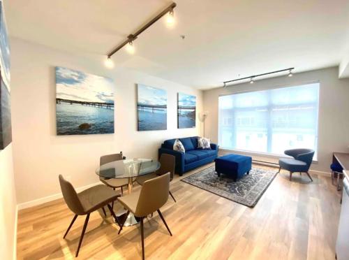 a living room with a blue couch and a table and chairs at Perfect Brand New Condo In The Heart of Sidney in Sidney