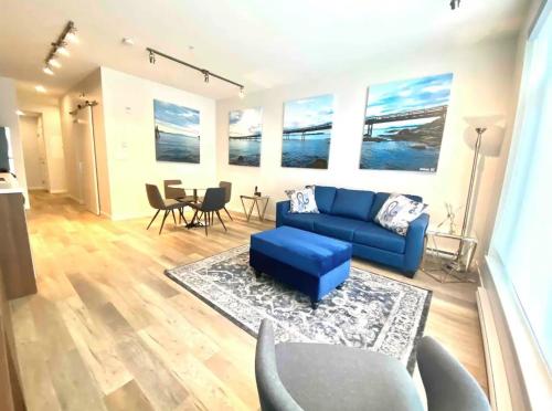 a living room with a blue couch and a table at Perfect Brand New Condo In The Heart of Sidney in Sidney