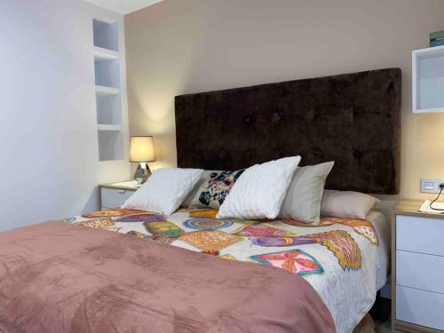 a bedroom with a large bed with a large headboard at Apartamento a 100metros de la playa de San Lorenzo in Gijón