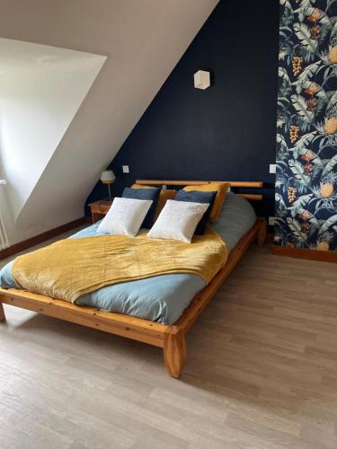 um quarto com uma grande cama de madeira com almofadas em Ti sterennou Maison néo bretonne rénovée proche axe Paris Brest RN12 et tgv 