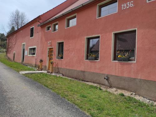 a red building with flowers in windows on a street at Ranč Červený mlýn in Lisov