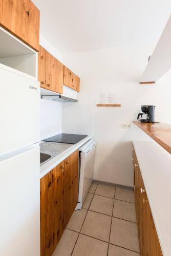 a kitchen with white walls and wooden cabinets at La Tour de Guet in Montbrun-les-Bains
