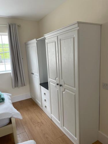 a bedroom with white cabinets and a bed and a window at Hillside House- Pine View in Ballinamuck