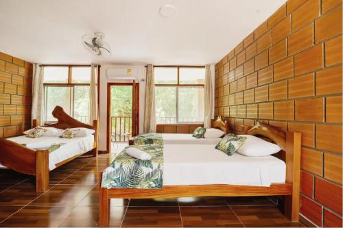 1 dormitorio con 2 camas y una pared de ventanas en Arca Tayrona Restaurant & Hostal, en Santa Marta