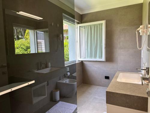 bagno con lavandino, servizi igienici e finestra di Hotel Riviera a Magnano in Riviera