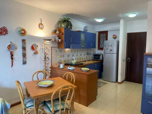 una cucina con armadi blu, tavolo e frigorifero di Blue Taormina Holiday a Letoianni