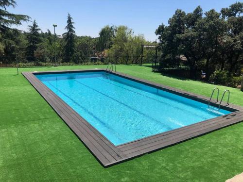 a swimming pool in a yard with green grass at Villa Rana, con amplio jardín, barbacoa y piscina in Valdemorillo