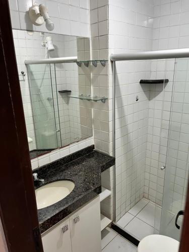 y baño con lavabo y ducha con espejo. en Monte Castelo Flat 08B, en Gravatá