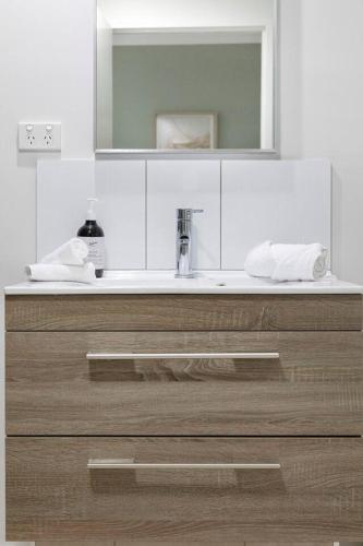 a bathroom with a sink and a mirror at 'Opal of Darwin' Breezy Living Atop Blue Horizons in Darwin